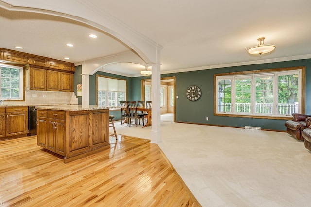 989 Kadler Ave NE, Saint Michael, MN 55376 - kitchen featuring brown cabinetry, a breakfast bar area, light wood-type flooring, ornamental molding, and healthy amount of natural light