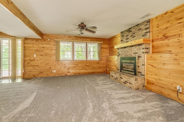 989 Kadler Ave NE, Saint Michael, MN 55376 - unfurnished living room with a ceiling fan, wood walls, a textured ceiling, a brick fireplace, and carpet flooring