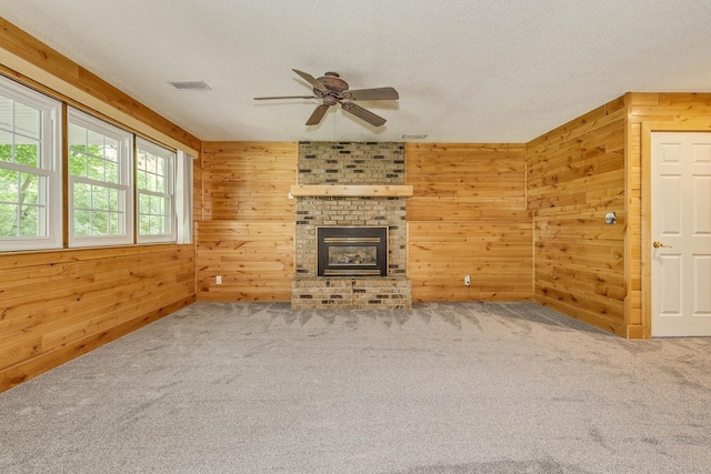 989 Kadler Ave NE, Saint Michael, MN 55376 - unfurnished living room featuring wooden walls, a ceiling fan, a textured ceiling, carpet, and a brick fireplace
