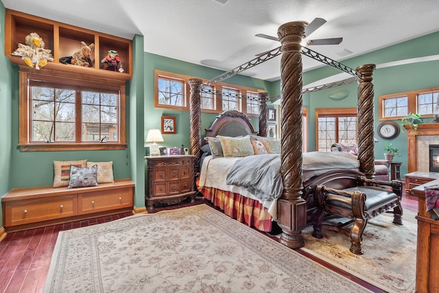 12322 Coffee Trl, Rosemount, MN 55068 - bedroom featuring dark wood finished floors, ornate columns, a glass covered fireplace, and a ceiling fan