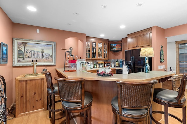 12322 Coffee Trl, Rosemount, MN 55068 - kitchen with black refrigerator with ice dispenser, glass insert cabinets, light countertops, light wood-style flooring, and a peninsula