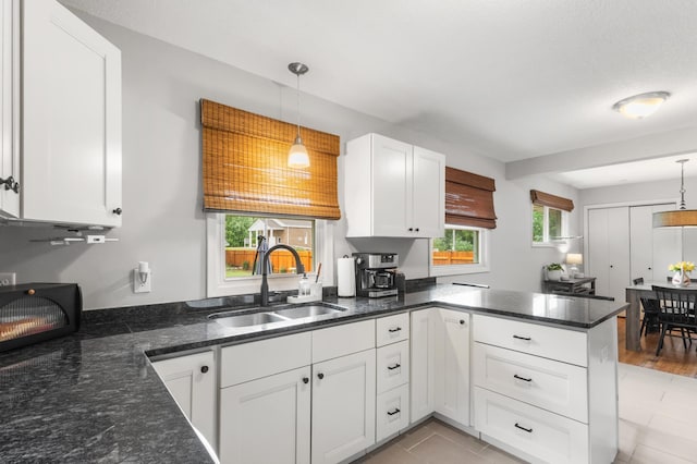 4633 Ewing Ave N, Robbinsdale, MN 55422 - kitchen with a peninsula, white cabinets, pendant lighting, and dark stone counters