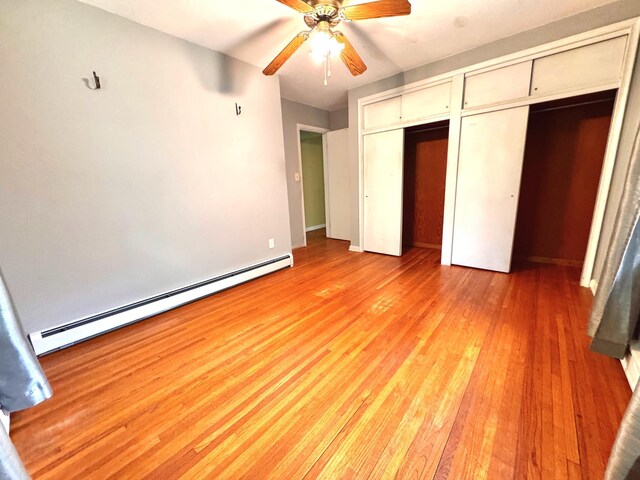300 Lyon St, Minneota, MN 56264 - unfurnished bedroom featuring a baseboard heating unit, multiple closets, light wood-style floors, and a ceiling fan