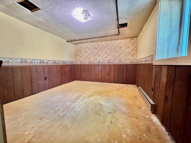 300 Lyon St, Minneota, MN 56264 - basement with baseboard heating, a wainscoted wall, wood walls, and a textured ceiling