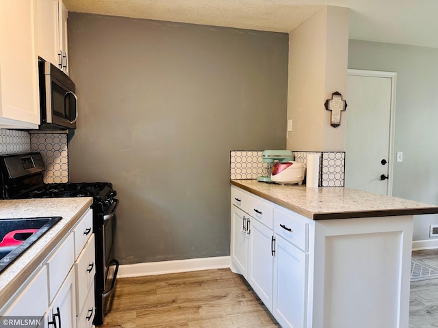 10701 6th St NE, Blaine, MN 55434 - kitchen with gas range oven, a peninsula, decorative backsplash, light wood-style floors, and white cabinets
