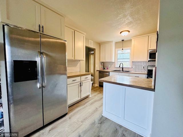 10701 6th St NE, Blaine, MN 55434 - kitchen featuring stainless steel appliances, light wood finished floors, tasteful backsplash, white cabinetry, and a textured ceiling