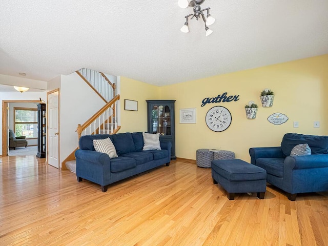 18232 Roosevelt St NW, Elk River, MN 55330 - living room with light wood-style flooring, stairs, a textured ceiling, and a chandelier