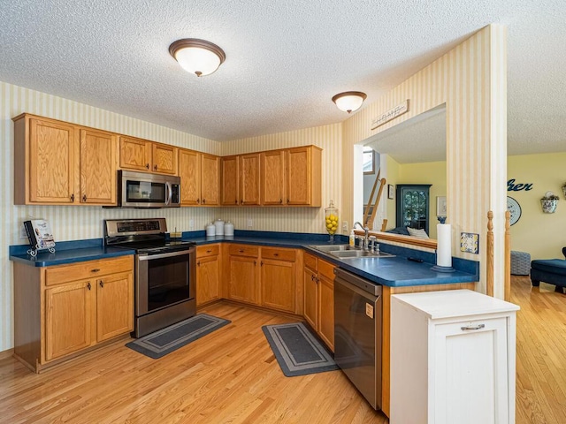 18232 Roosevelt St NW, Elk River, MN 55330 - kitchen featuring stainless steel appliances, a textured ceiling, dark countertops, light wood-style flooring, and brown cabinets