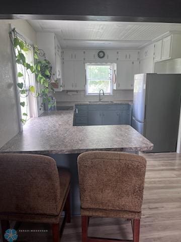 72558 209th St, Collinwood Twp, MN 55325 - kitchen with freestanding refrigerator, a peninsula, light wood-style floors, and white cabinets