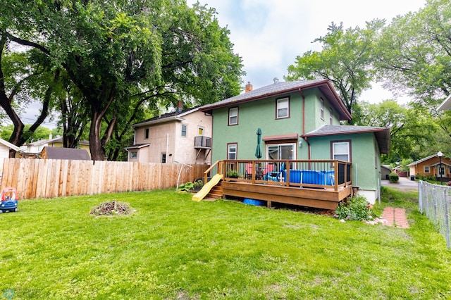 1205 11th St S, Fargo, ND 58103 - rear view of house with stucco siding, a fenced backyard, a wooden deck, and a chimney