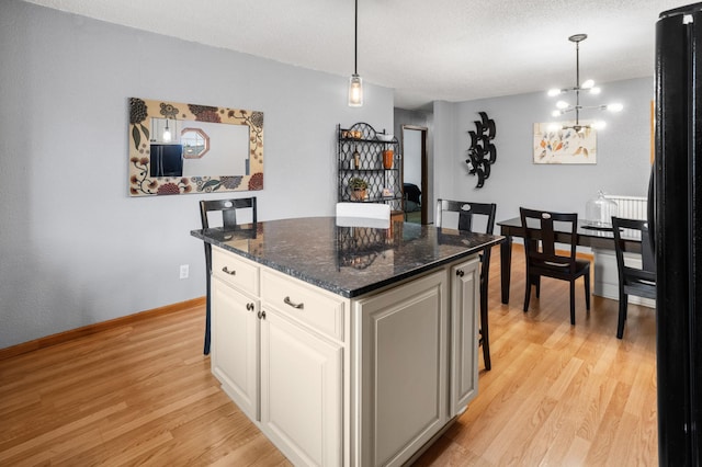 2900 16th Ave S, Moorhead, MN 56560 - kitchen featuring light wood finished floors, a kitchen island, white cabinetry, decorative light fixtures, and freestanding refrigerator