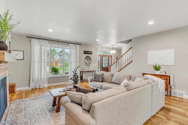 6728 Ashwood Loop, Fargo, ND 58104 - living room featuring stairs, a chandelier, a fireplace, light wood-style flooring, and recessed lighting