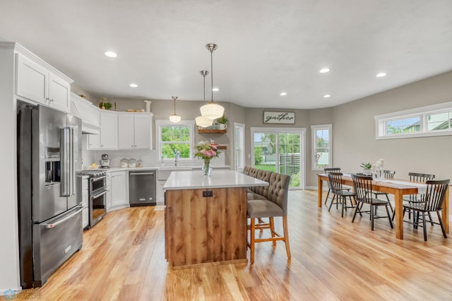 6728 Ashwood Loop, Fargo, ND 58104 - kitchen featuring stainless steel appliances, light countertops, a breakfast bar area, light wood-style floors, and recessed lighting