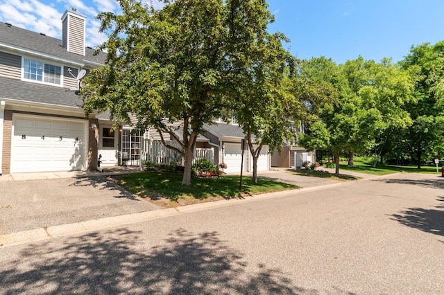 8454 Copperfield Way Unit 75, Inver Grove Heights, MN 55076 - view of front of property with driveway, brick siding, a shingled roof, and a chimney