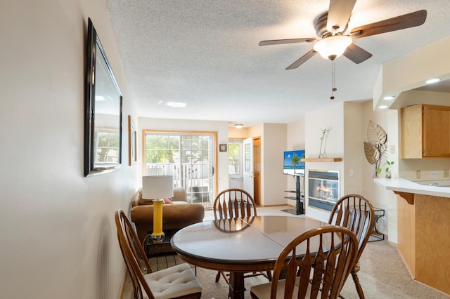 8454 Copperfield Way Unit 75, Inver Grove Heights, MN 55076 - dining area with a ceiling fan, a textured ceiling, a fireplace with flush hearth, and light carpet