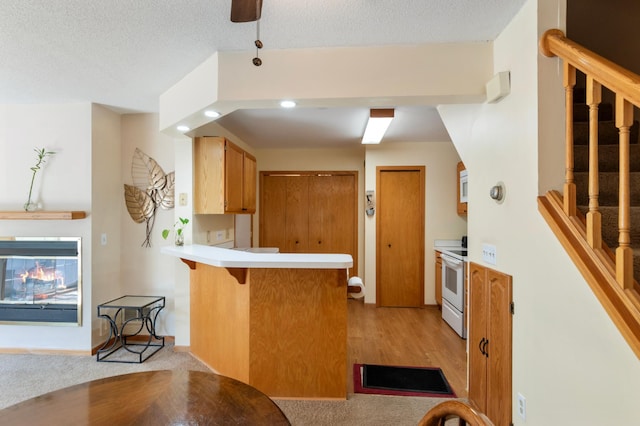 8454 Copperfield Way Unit 75, Inver Grove Heights, MN 55076 - kitchen with a peninsula, light countertops, white range with electric stovetop, a kitchen breakfast bar, and light colored carpet