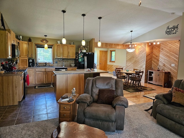 611 3rd St SW, Richville, MN 56576 - kitchen featuring open floor plan, black appliances, wooden walls, lofted ceiling, and a center island