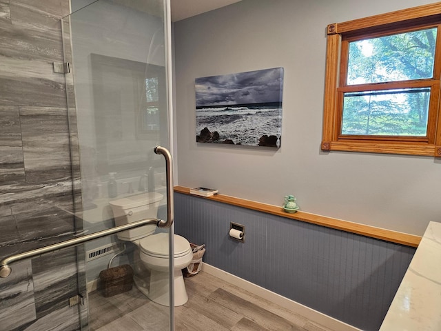 611 3rd St SW, Richville, MN 56576 - bathroom featuring wood finished floors, an enclosed shower, and a wainscoted wall