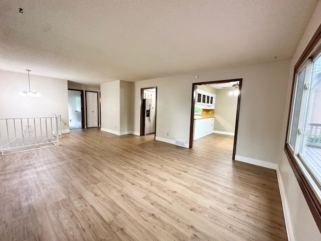 2360 3rd St NW, New Brighton, MN 55112 - unfurnished room featuring a textured ceiling, light wood-style flooring, plenty of natural light, a ceiling fan, and a chandelier