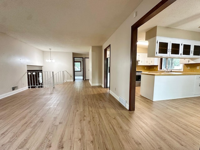 2360 3rd St NW, New Brighton, MN 55112 - unfurnished living room with light wood-style flooring, a textured ceiling, and a chandelier