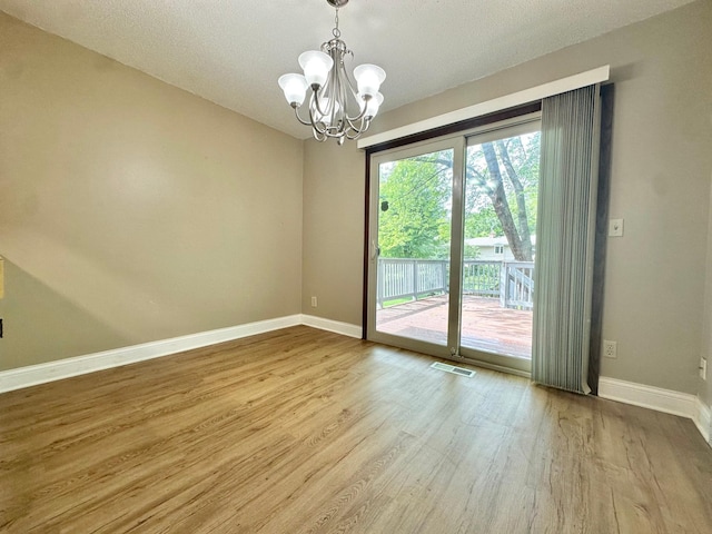 2360 3rd St NW, New Brighton, MN 55112 - unfurnished room with wood finished floors, a chandelier, and a textured ceiling
