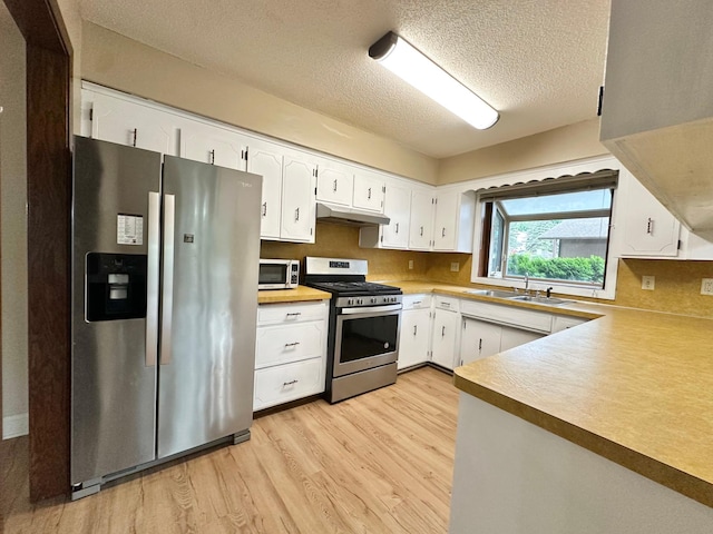 2360 3rd St NW, New Brighton, MN 55112 - kitchen with stainless steel appliances, under cabinet range hood, light wood-type flooring, a textured ceiling, and white cabinetry
