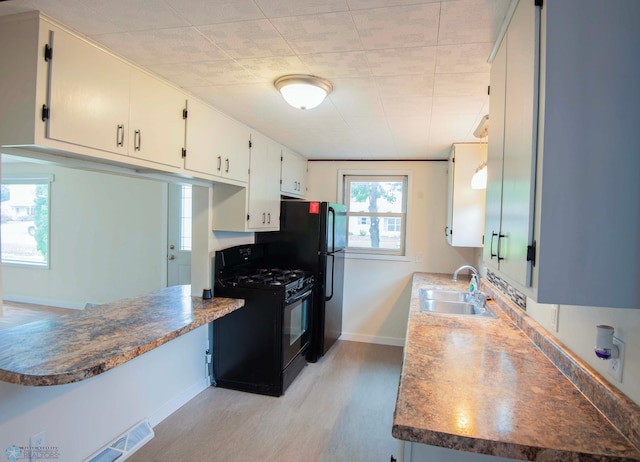405 18th St N, Moorhead, MN 56560 - kitchen featuring black appliances, light wood-style flooring, and white cabinets