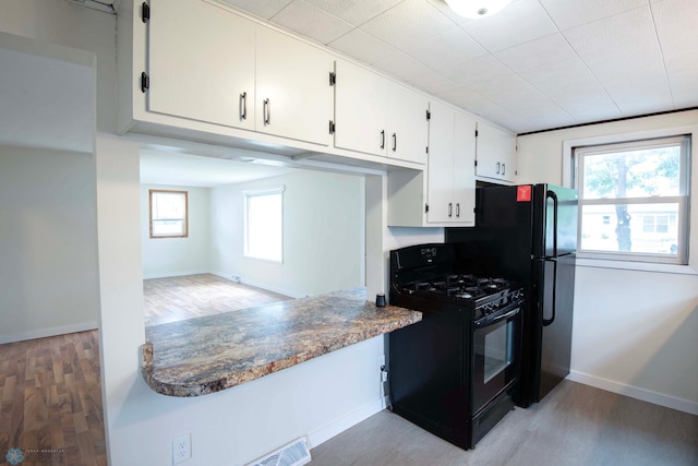 405 18th St N, Moorhead, MN 56560 - kitchen with black gas range, light wood-style flooring, white cabinets, and healthy amount of natural light