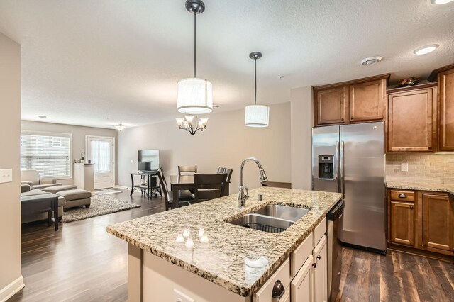 9902 5th Street Ln N, Lake Elmo, MN 55042 - kitchen with appliances with stainless steel finishes, dark wood finished floors, brown cabinetry, backsplash, and hanging light fixtures