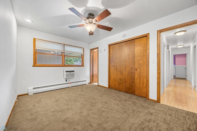 2319 10th St S, Fargo, ND 58103 - unfurnished bedroom featuring a baseboard heating unit, a wall unit AC, light colored carpet, a ceiling fan, and a closet