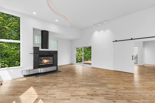 3520 Fairway Ln, Minnetonka, MN 55305 - unfurnished living room featuring rail lighting, light wood finished floors, a barn door, a fireplace, and recessed lighting