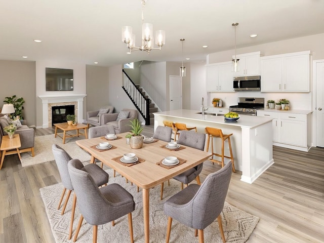 3237 Jandura Ave NE, Saint Michael, MN 55376 - dining room featuring stairs, light wood-type flooring, recessed lighting, a chandelier, and a glass covered fireplace