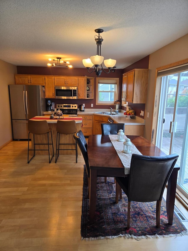 10641 Able St NE, Blaine, MN 55434 - dining room with light wood-style floors, a chandelier, and a textured ceiling