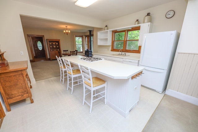 1122 Fillmore St, Alexandria, MN 56308 - kitchen featuring white appliances, white cabinetry, a kitchen bar, a chandelier, and a kitchen island