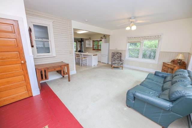1122 Fillmore St, Alexandria, MN 56308 - living area featuring ceiling fan, a wainscoted wall, wood walls, and stairs