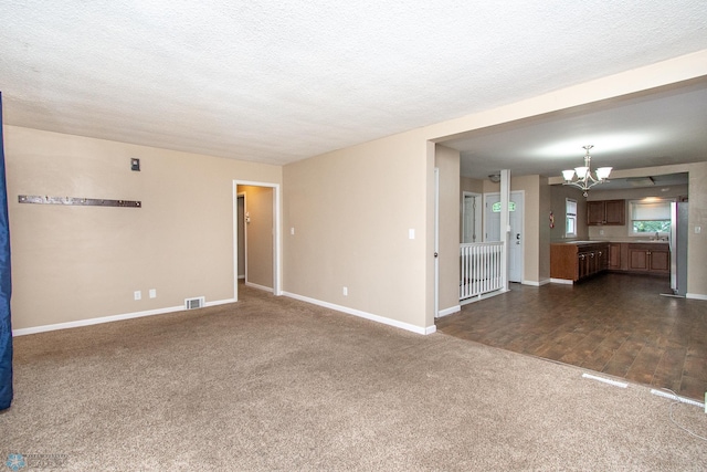 634 11th St N, Moorhead, MN 56560 - unfurnished living room featuring a chandelier, dark carpet, and a textured ceiling