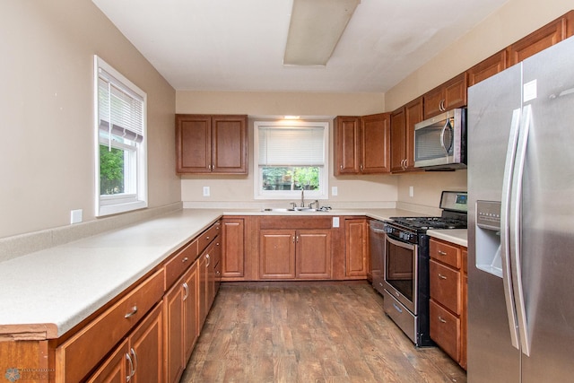 634 11th St N, Moorhead, MN 56560 - kitchen with appliances with stainless steel finishes, healthy amount of natural light, dark wood-style floors, and brown cabinets