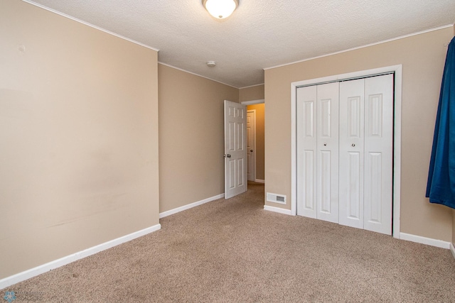 634 11th St N, Moorhead, MN 56560 - unfurnished bedroom featuring carpet floors, crown molding, a closet, and a textured ceiling