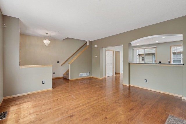 11350 Stratton Ave, Eden Prairie, MN 55344 - unfurnished living room featuring arched walkways, wood finished floors, stairway, and a chandelier