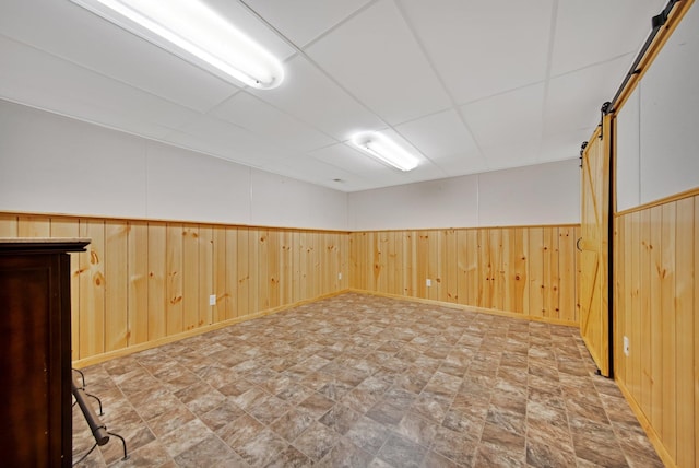 14136 Germane Ave, Apple Valley, MN 55124 - empty room featuring a barn door, wooden walls, stone finish flooring, and wainscoting