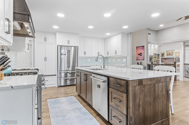 3020 26th Ave S, Fargo, ND 58103 - kitchen featuring appliances with stainless steel finishes, white cabinetry, tasteful backsplash, an island with sink, and light wood finished floors