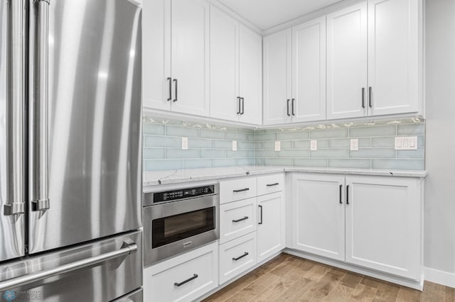 3020 26th Ave S, Fargo, ND 58103 - kitchen featuring freestanding refrigerator, tasteful backsplash, white cabinets, light stone countertops, and wall oven