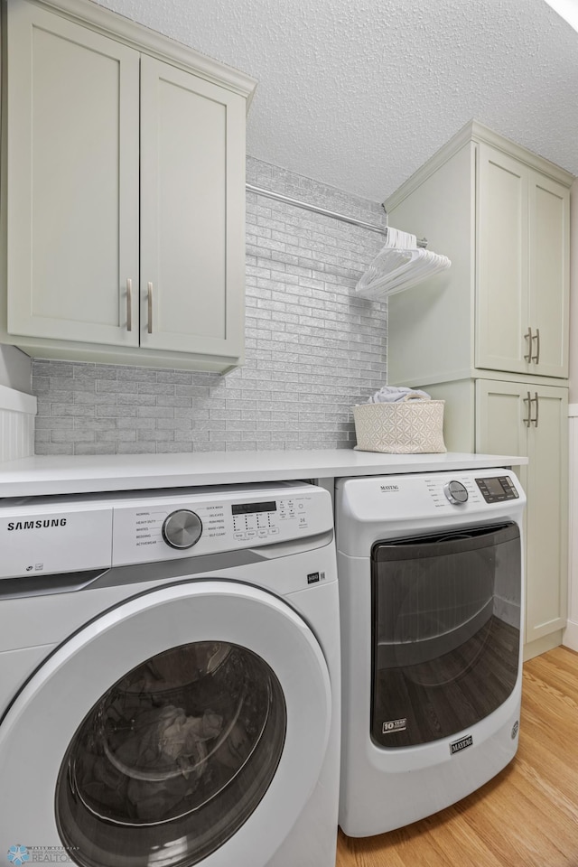 3020 26th Ave S, Fargo, ND 58103 - laundry room featuring washing machine and dryer, cabinet space, light wood-style floors, and a textured ceiling
