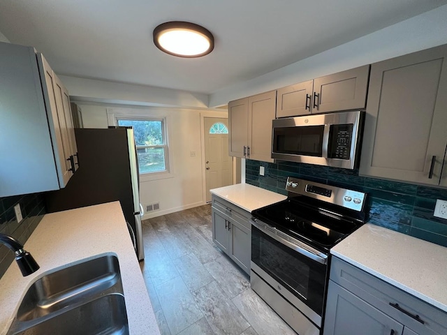 5923 Hodgson Rd, Shoreview, MN 55126 - kitchen with stainless steel appliances, gray cabinets, light countertops, and decorative backsplash