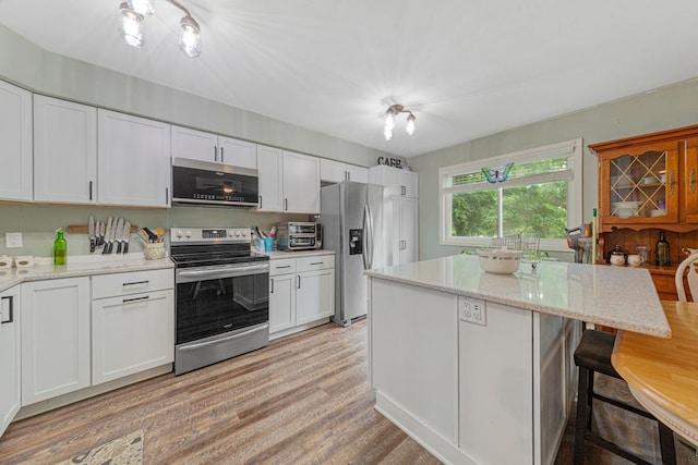 1030 Barron Rd, Faribault, MN 55021 - kitchen featuring stainless steel appliances, white cabinetry, a breakfast bar, and light wood-style floors