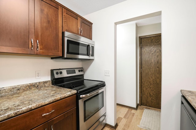 205 Barry Ave S Unit 208, Wayzata, MN 55391 - kitchen featuring appliances with stainless steel finishes, light wood finished floors, and light stone countertops