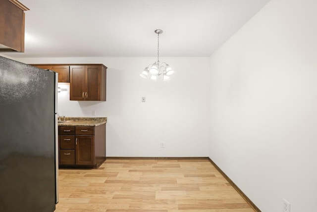 205 Barry Ave S Unit 208, Wayzata, MN 55391 - kitchen with freestanding refrigerator, light wood finished floors, a chandelier, dark brown cabinets, and pendant lighting