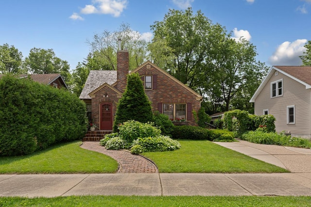 825 5th Ave SW, Faribault, MN 55021 - tudor-style house featuring brick siding, a front lawn, and a chimney