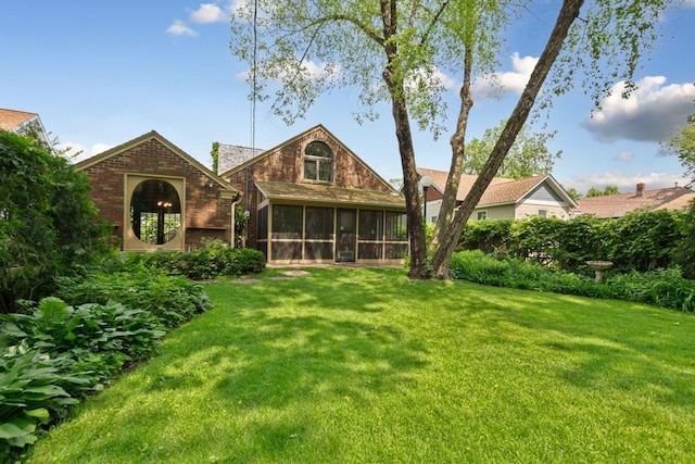 825 5th Ave SW, Faribault, MN 55021 - back of property with a sunroom, brick siding, and a yard