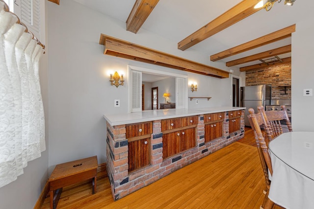 825 5th Ave SW, Faribault, MN 55021 - kitchen featuring freestanding refrigerator, light wood finished floors, beam ceiling, brown cabinets, and light countertops